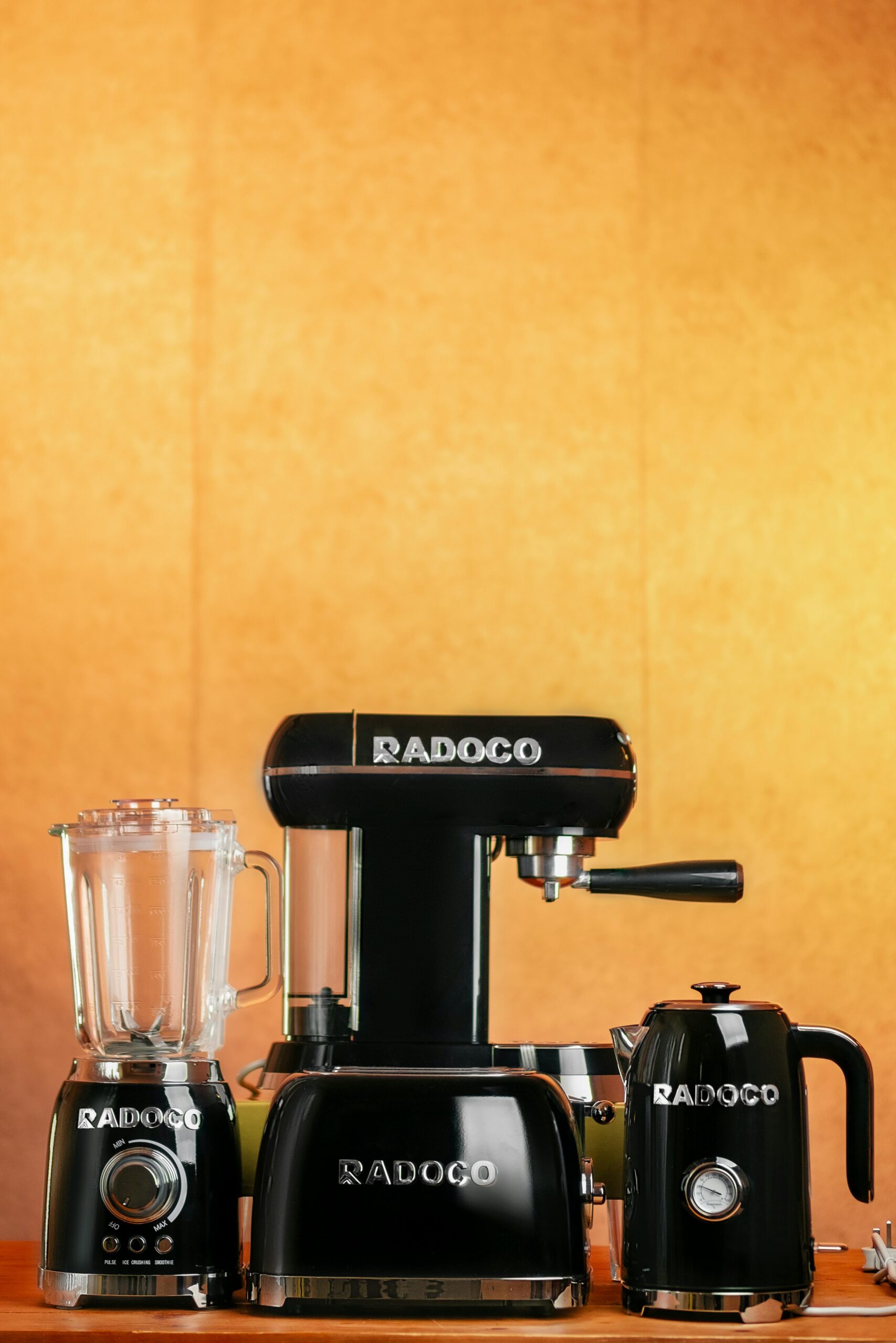 Modern black kitchen appliances including blender, mixer, and kettle with warm background.